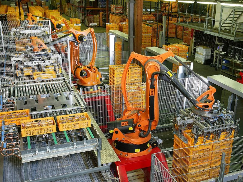 Orange industrial robot arms working on a factory production line